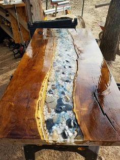 a wooden table with rocks and water running down the center, in front of a tree