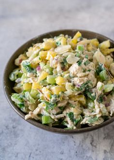 a close up of a bowl of food on a table with broccoli and chicken salad