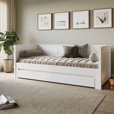 a white daybed sitting on top of a wooden floor next to a potted plant