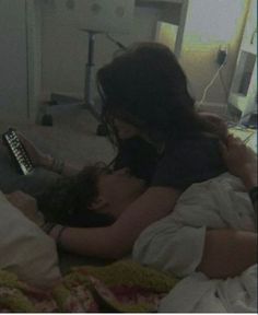 a woman laying in bed next to a man with a remote control on his chest