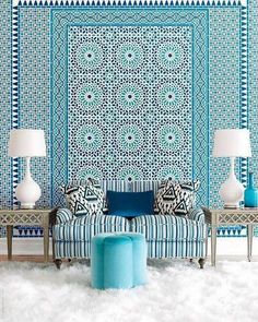 a blue and white couch sitting in front of a wall with a pattern on it