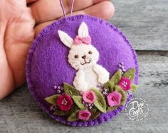 a hand holding a purple ornament with a white rabbit on it