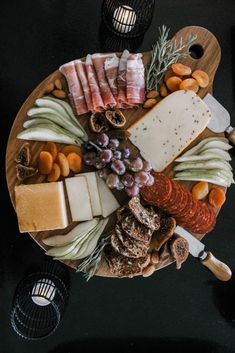 a platter with cheese, meats and grapes on it