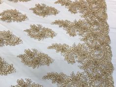 an embroidered fabric with gold flowers and leaves on white background, closeup shot from the neck down