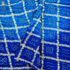 Fabric: Gajji Silk Weave – Bandhani with Ajrakh Pallu Color –Blue & Red Blouse – Ajrakh Note- There may be slight color variations due to photographic reasons. This is a hand-woven product and any irregularities in the weaving or pattern should not be taken as a defect. These irregularities make every handloom piece unique. Blue Bandhani Chanderi Salwar Kameez, Blue Bandhani Print Chanderi Salwar Kameez, Unstitched Batik Print Traditional Wear For Navratri, Traditional Blue Saree With Batik Print, Blue Bandhani Print Salwar Kameez For Navratri, Traditional Blue Batik Print Saree, Bollywood Style Batik Print Traditional Wear For Navratri, Bollywood Style Traditional Wear With Batik Print For Navratri, Festive Blue Batik Print Saree