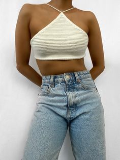 a woman in jeans and a crop top posing for the camera with her hands on her hips