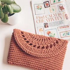 a crocheted purse sitting on top of a white table next to a plant