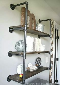 an industrial pipe shelving unit in the corner of a room with white walls and black pipes