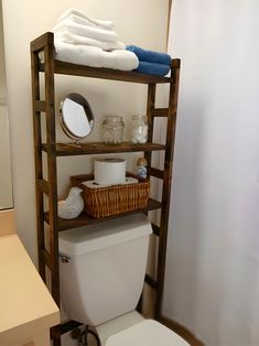 a bathroom with a wooden shelf over the toilet