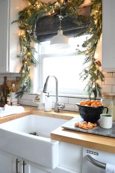 a kitchen decorated for christmas with garland and oranges on the sink window sill