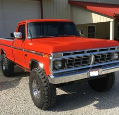 an orange pick up truck parked in front of a garage