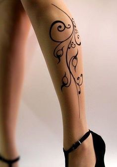 a woman's legs with tattoos and high heels on her feet is seen in this image