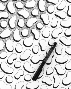 a black pen sitting on top of a white paper with an abstract pattern in the background