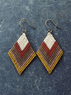 a pair of beaded earrings on top of a blue surface with white and red squares