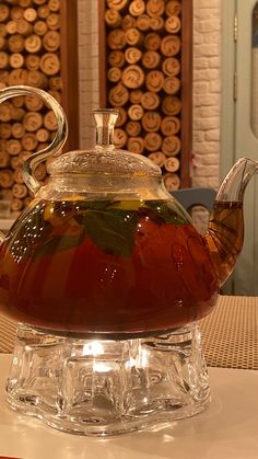 a glass tea pot filled with liquid sitting on top of a table