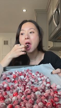 a woman making a funny face in front of a tray of cranberries