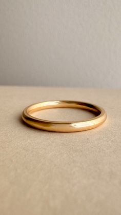 two gold wedding bands sitting on top of a white surface with a light colored wall in the background