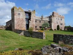 an old castle like building sitting on top of a lush green field