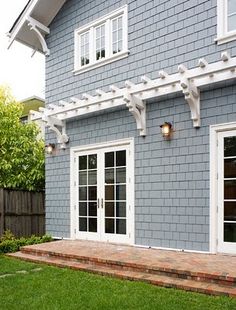 a blue house with white trim and an attached pergolated trellis on the side