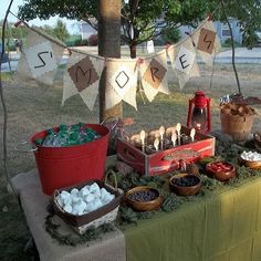 a picnic table with food on it and buntings hanging from the line above