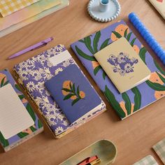 several notebooks and pens on a table next to each other, with flowers printed on them