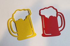 two beer mugs cut out of paper on a white surface with one red and one yellow