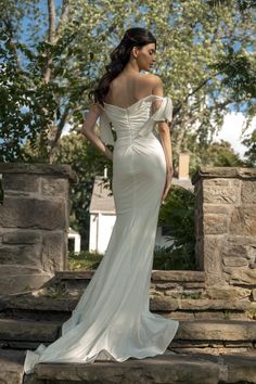 a woman in a white dress standing on some steps