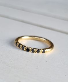 a yellow gold ring with black stones on the inside and outside, sitting on a white surface