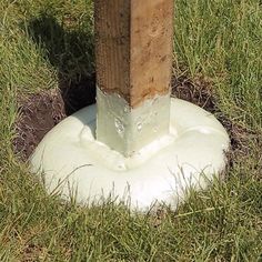 a wooden post sticking out of the ground next to a hole in the green grass