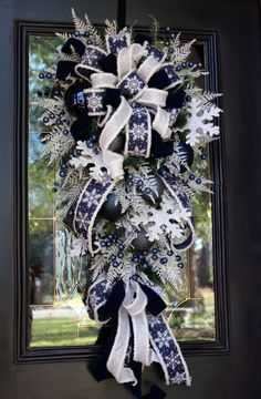 a blue and white christmas wreath hanging on the front door