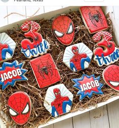 decorated cookies in a box with spiderman on them and name tags for each cookie