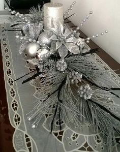 a candle is sitting on top of a table with silver decorations and pineconis