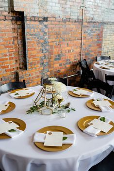 a white table topped with gold plates and place settings