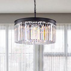 a chandelier hanging from the ceiling in a living room with curtains behind it