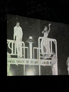 two men and a woman standing on top of a stage