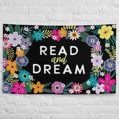 a sign that says read and dream with flowers around it on a white brick wall