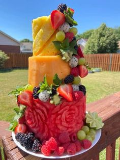 a cake made out of fruit on top of a wooden table in the grass outside