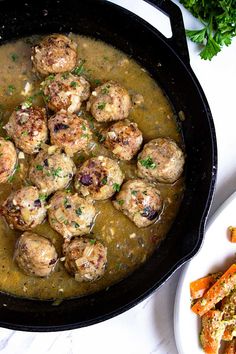 meatballs and carrots are in a skillet with gravy on the side