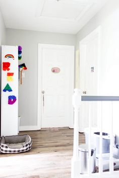 an empty room with white walls and wooden flooring, painted rainbows on the door