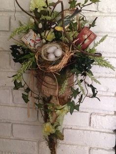 a bird's nest with eggs and flowers on a brick wall