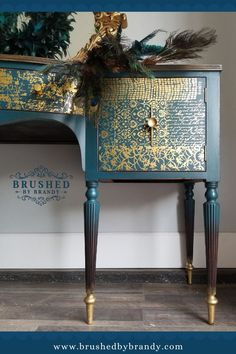 an ornate blue and gold chest of drawers with feathers on the top, next to a potted plant