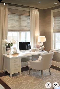 a white desk with a computer on top of it in front of two large windows