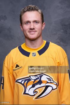 an ice hockey player poses for a headshot in his uniform, wearing the nashville predators jersey