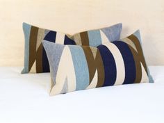 two blue and brown pillows sitting on top of a bed