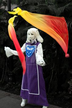 a person dressed as a wizard holding a long red and yellow streamer in their hand