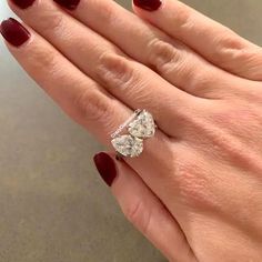 a woman's hand with red nail polish holding an engagement ring on her finger