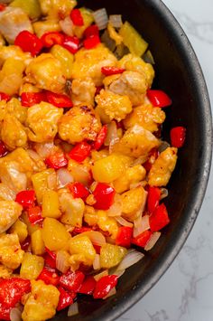 a pan filled with chicken and peppers on top of a table