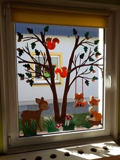 an image of a window decorated with paper animals and tree branches in the sun light