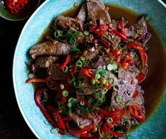 a blue plate topped with meat and veggies next to a bowl of sauce