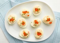 small appetizers are arranged on a white plate with blue napkins next to them